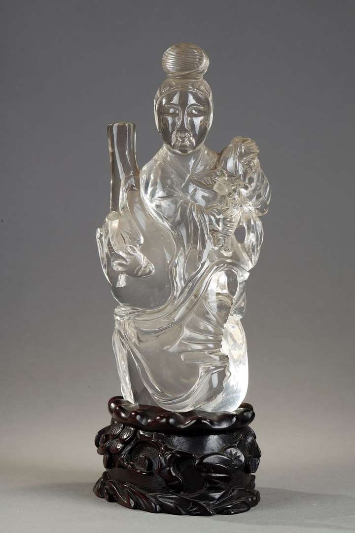 Rock crystal figure representing a guanyin holding a vase and a flower. Wooden base